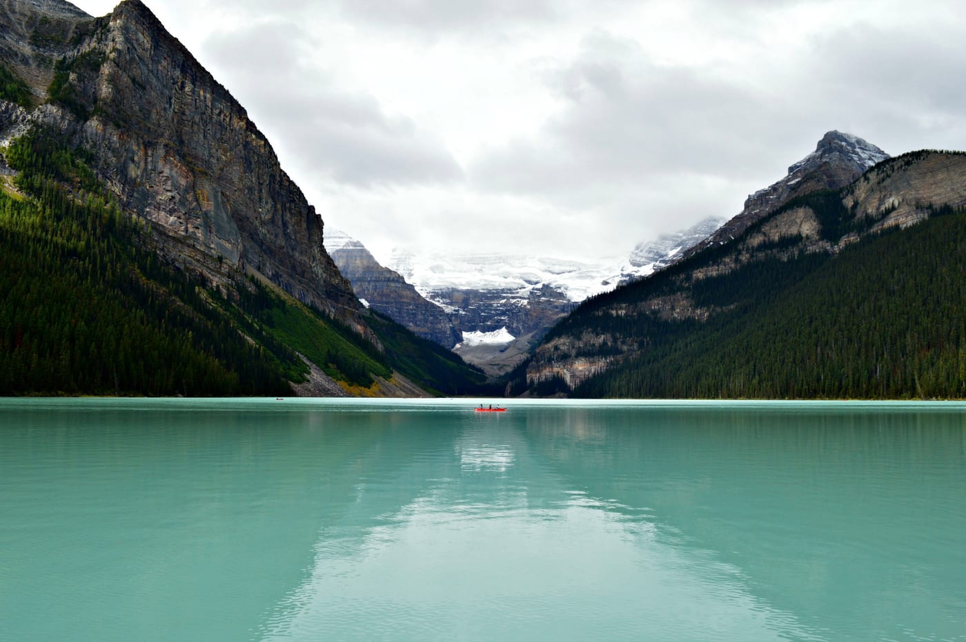 A boat on a turquoise lake below mountains