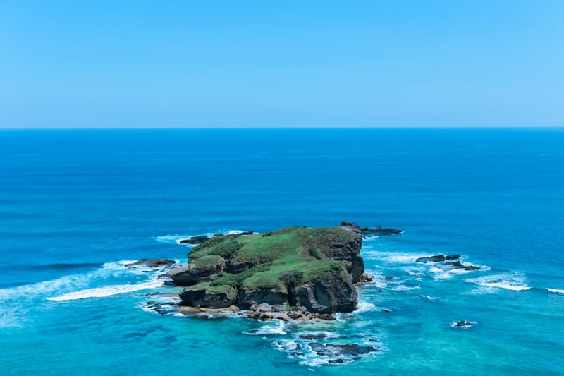 A small green island in a deep blue sea