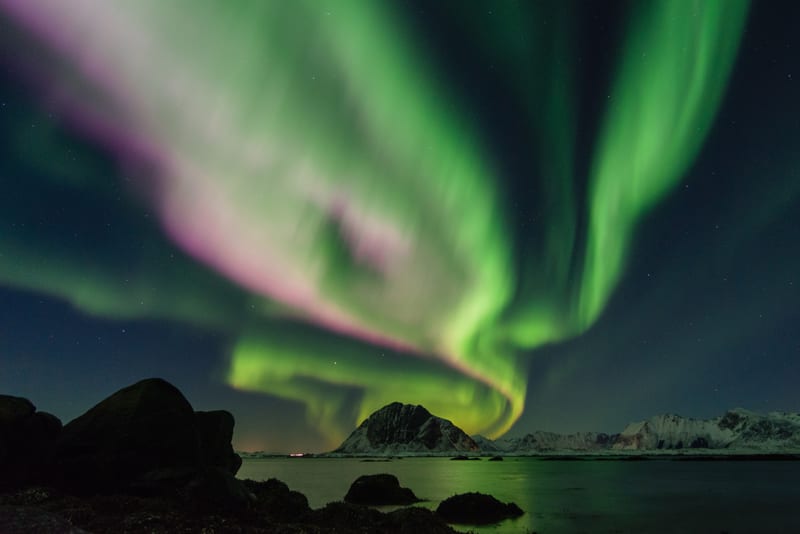Green northern lights over a rocky shore