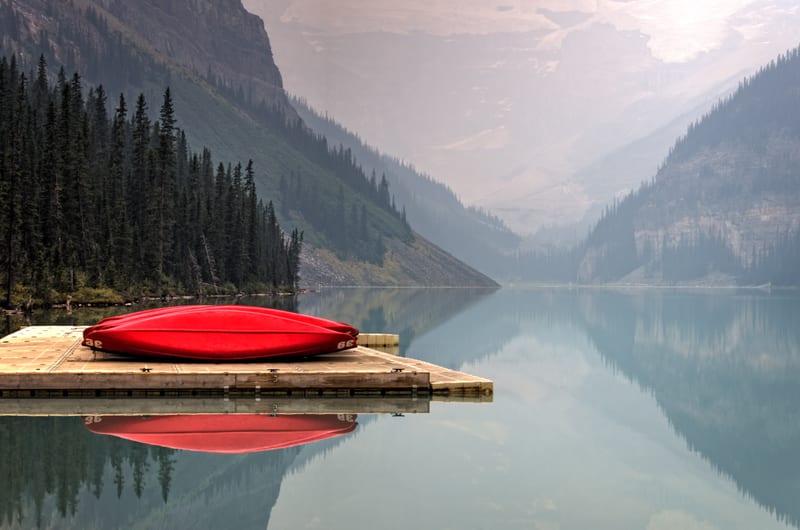Red kayaks on a dock by a misty mountain lake